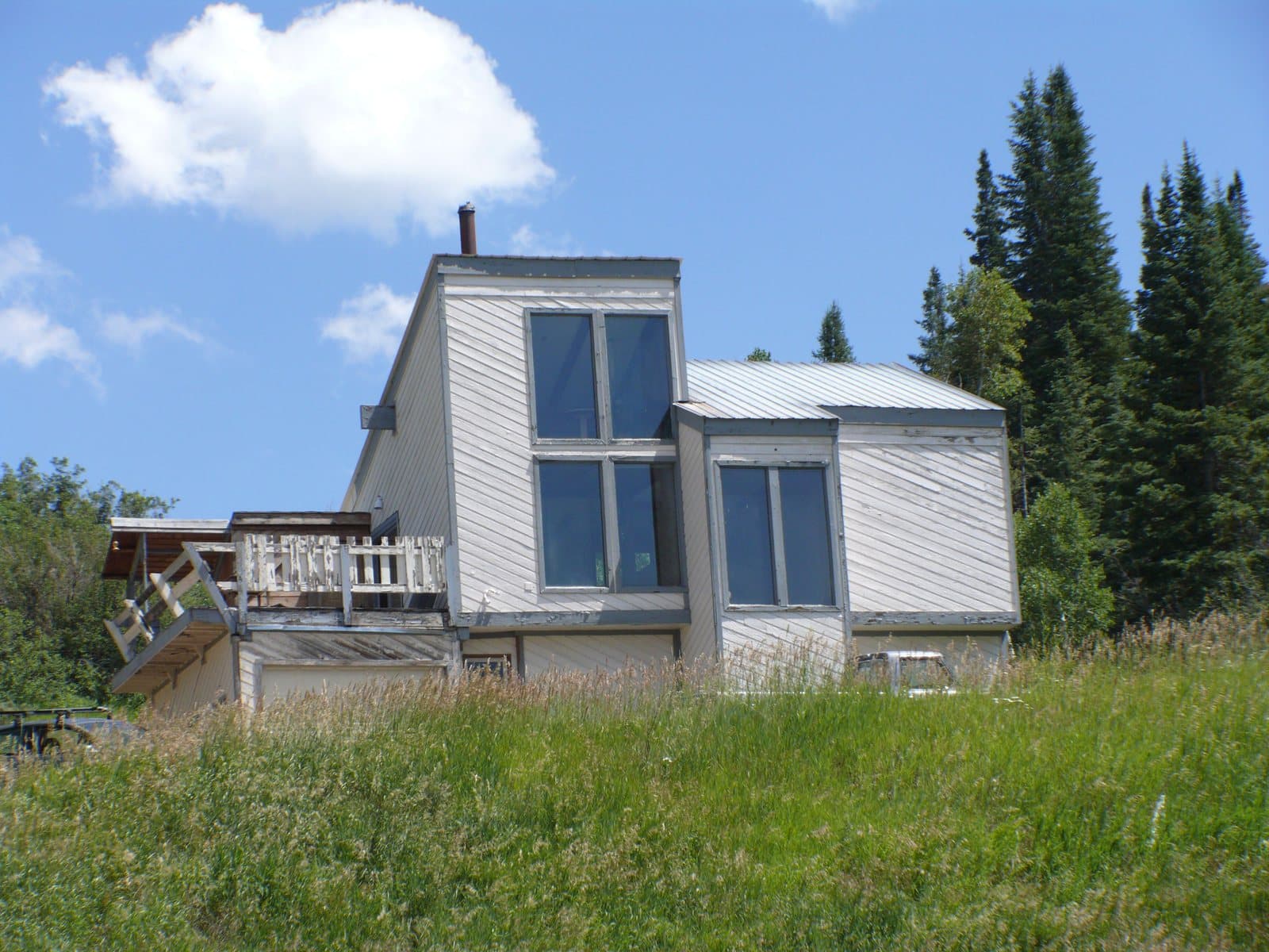 2009 snapshot of the existing house, then white, on a grassy slope